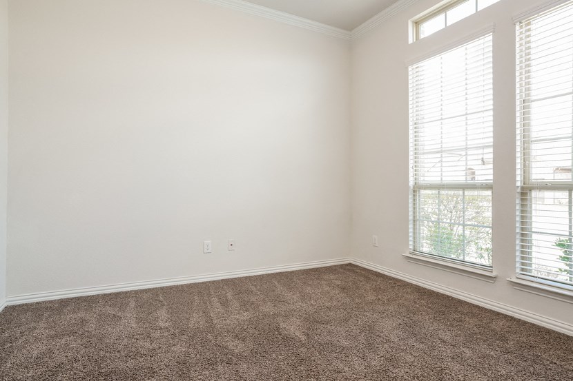 an empty room with carpet and two windows