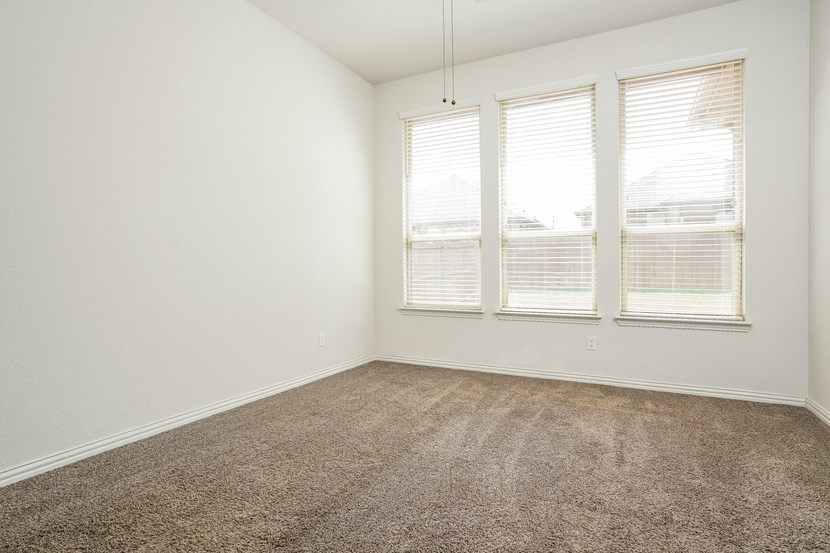an empty room with three windows and a carpeted floor
