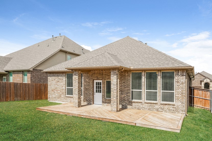a brick house with a wooden deck in the yard