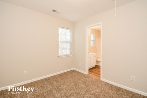 a bedroom with carpet and a door to a bathroom