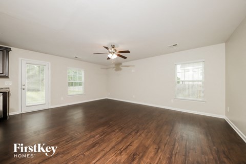 an empty living room with wood floors and a ceiling fan