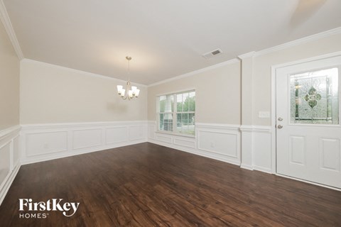the living room of a home with white walls and wood floors