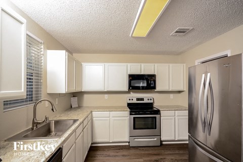 A kitchen with white cabinets and a stainless steel refrigerator.