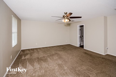 A spacious room with a ceiling fan and carpeted floor.