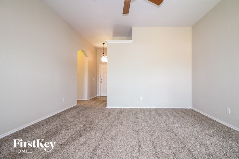 an empty living room with carpet and a ceiling fan