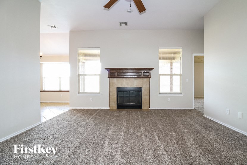 an empty living room with a fireplace and a carpeted floor