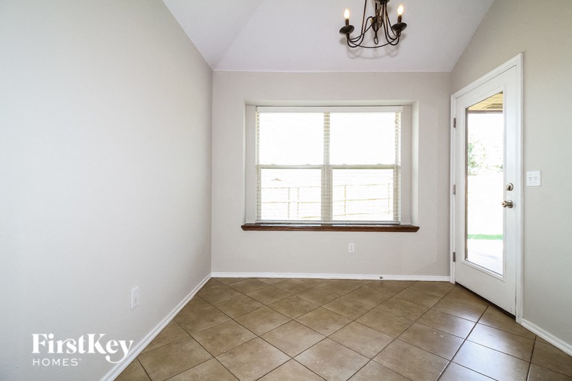 an empty dining room with a window and tiled floor