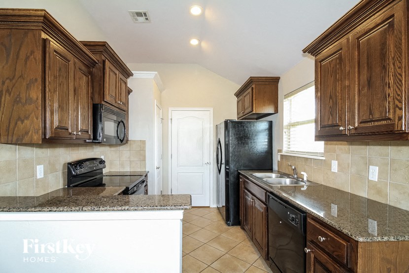 a kitchen with wooden cabinets and a black refrigerator