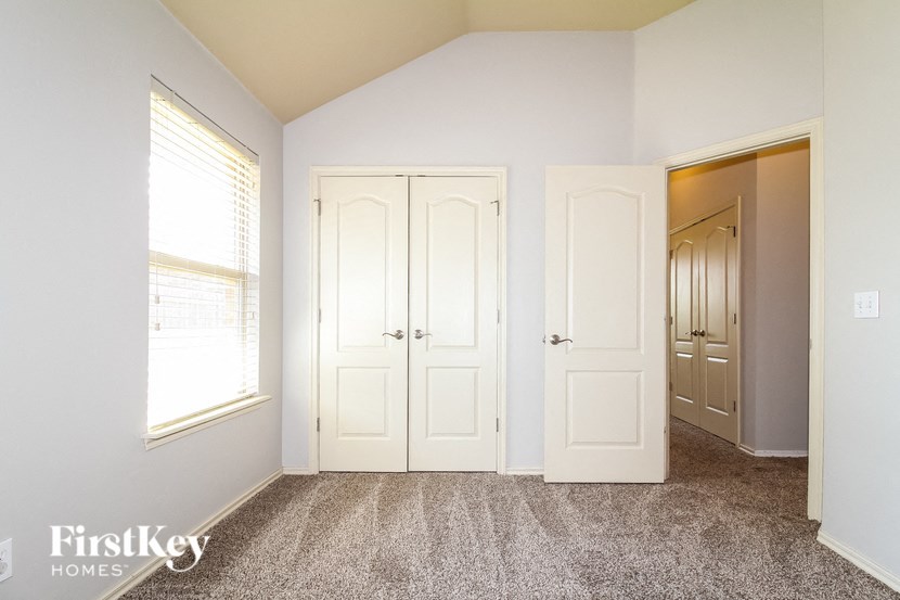 a bedroom with two closets and a window and a carpeted floor