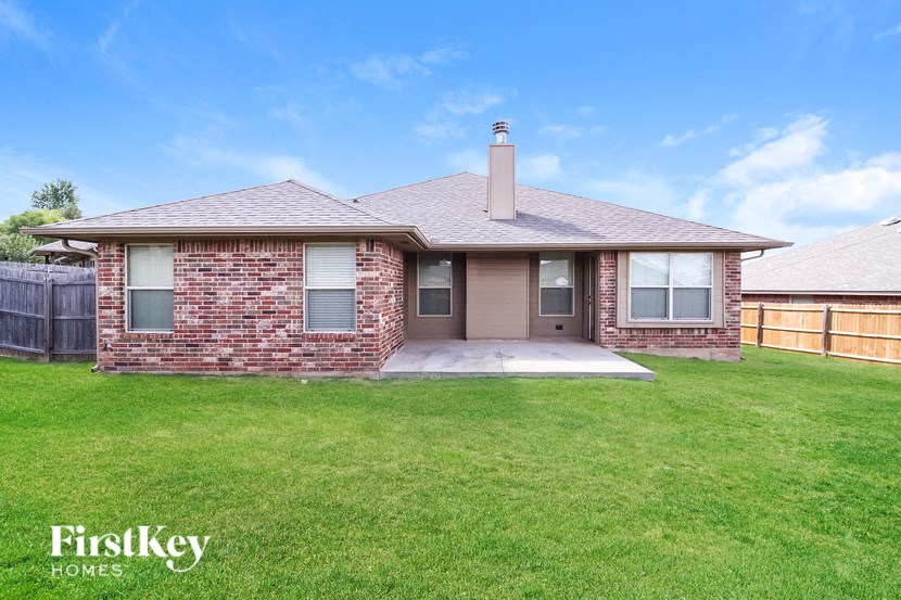 a small brick house with a lawn and a fence