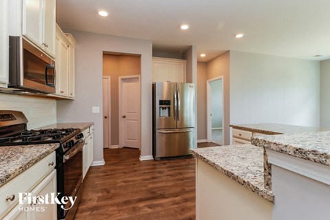 A kitchen with a granite counter top and wooden floors.