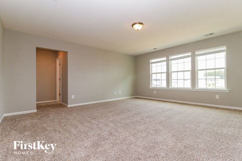 A spacious room with a carpeted floor and a door leading to another room.