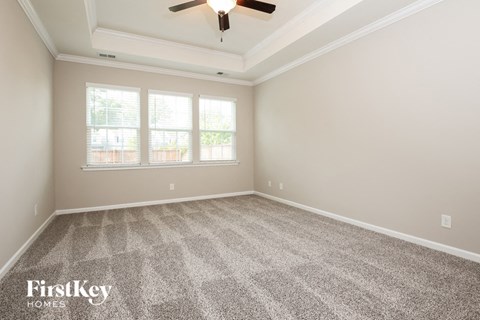 the living room of a new home with carpet and a ceiling fan