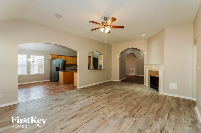 an empty living room with a fireplace and a ceiling fan