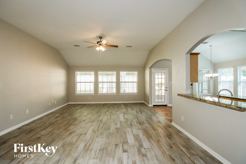 an empty living room with wood floors and a ceiling fan