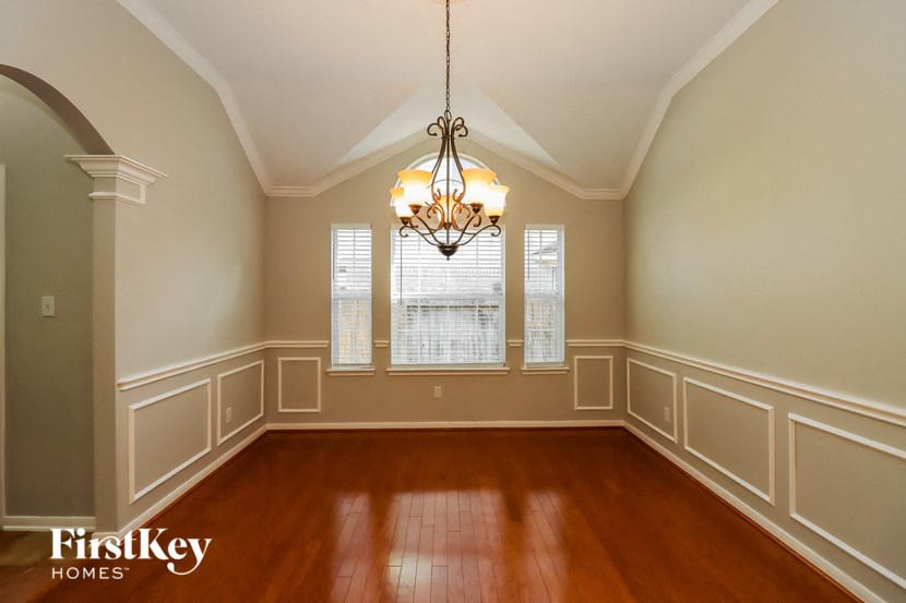 an empty dining room with wood floors and a chandelier