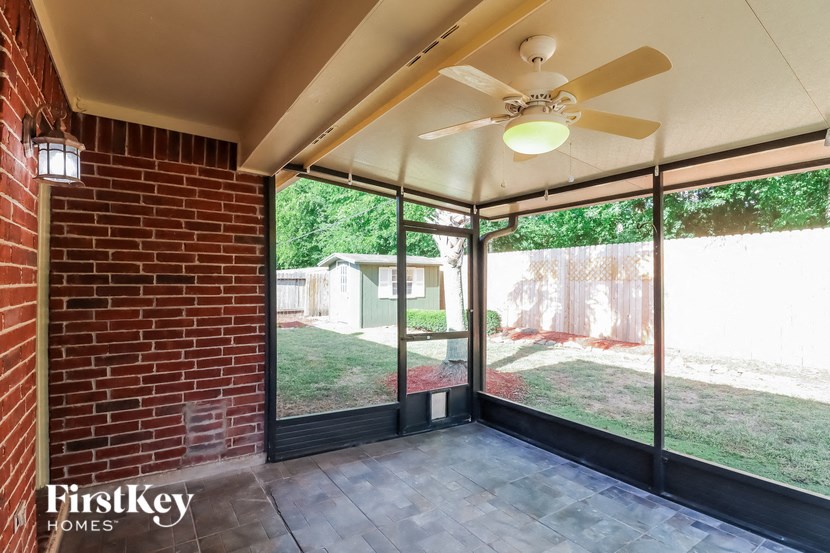an empty screened porch with a ceiling fan and glass doors