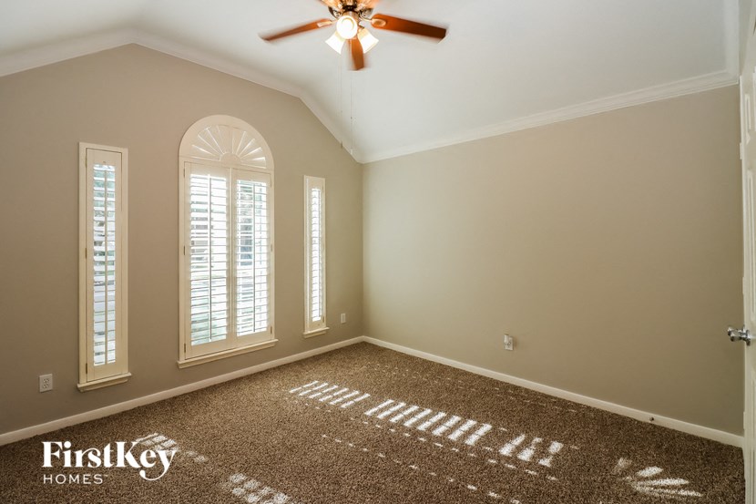 a empty living room with a ceiling fan and window