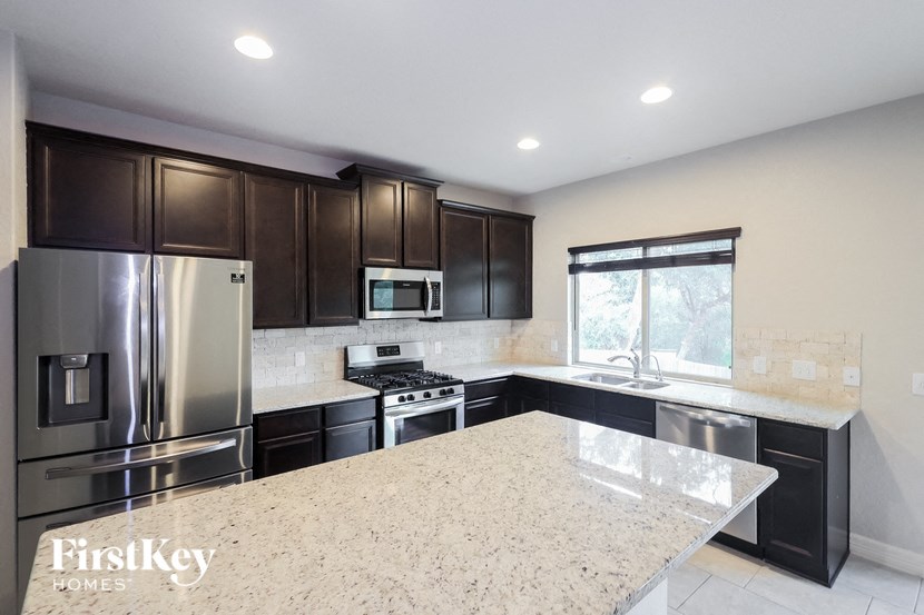A kitchen with a granite countertop and stainless steel appliances.