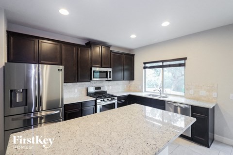 A kitchen with a granite countertop and stainless steel appliances.