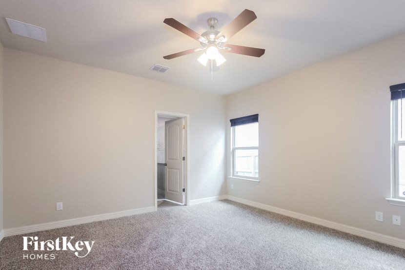 A spacious room with a ceiling fan and a door leading to another room.