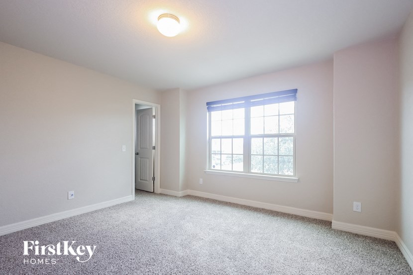 A room with a carpeted floor, a window, and a door.