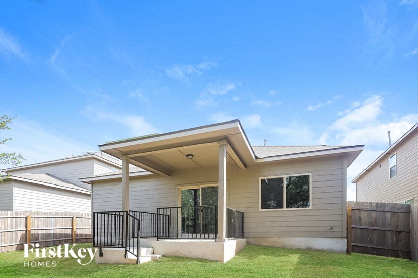 A house with a porch and a fence in front of it.