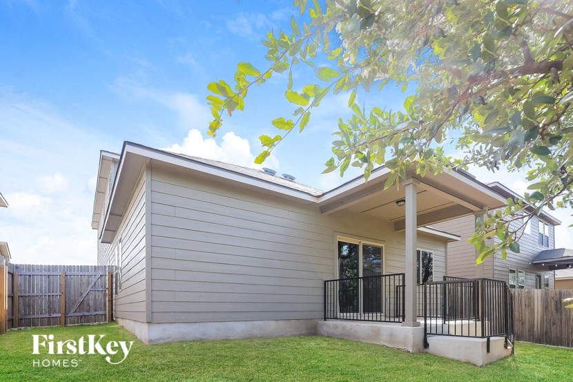 A house with a fence and a tree branch in the foreground.