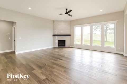 an empty living room with a fireplace and wooden floors