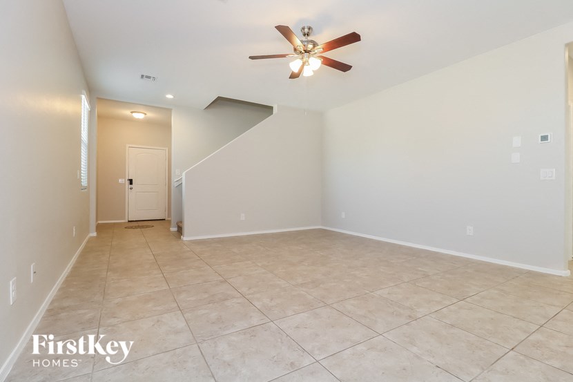 a empty living room with a ceiling fan and a tiled floor