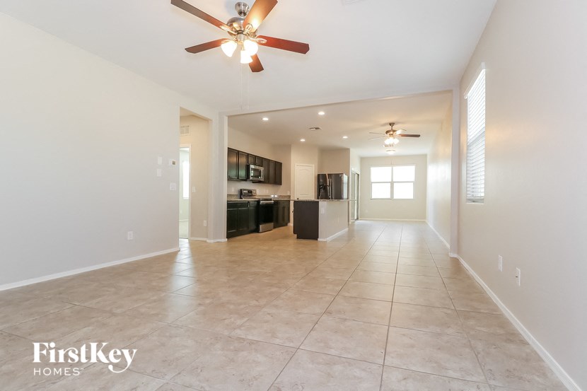 an empty living room and kitchen with a ceiling fan