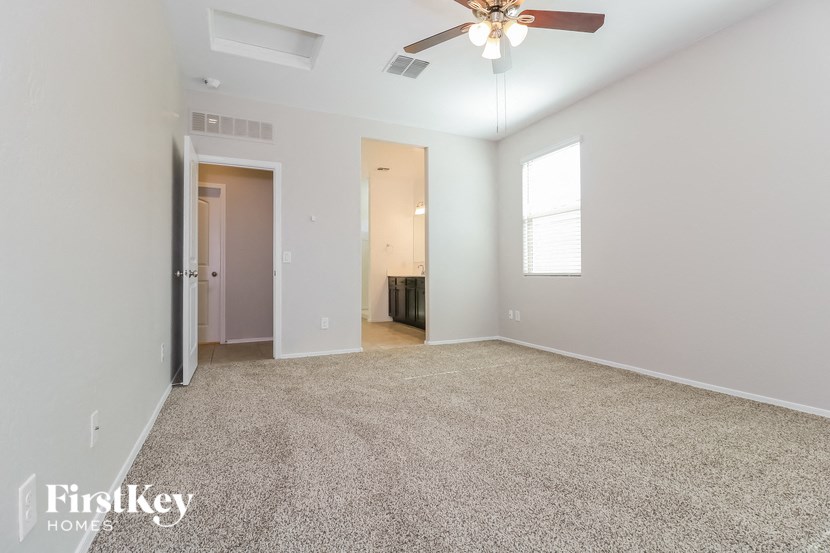 an empty living room with a ceiling fan and a window