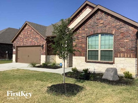 a brick house with a garage and a tree in the yard