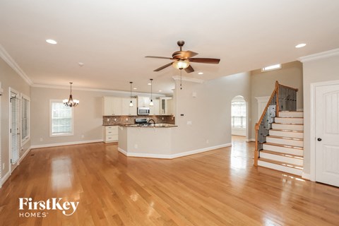 A spacious living room with a wooden floor and a staircase leading to the upper floor.