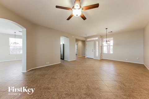 A spacious room with a ceiling fan and light fixture, and a large window with blinds.