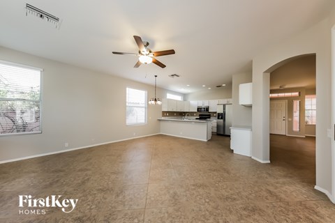 A spacious living room with a kitchen in the background.