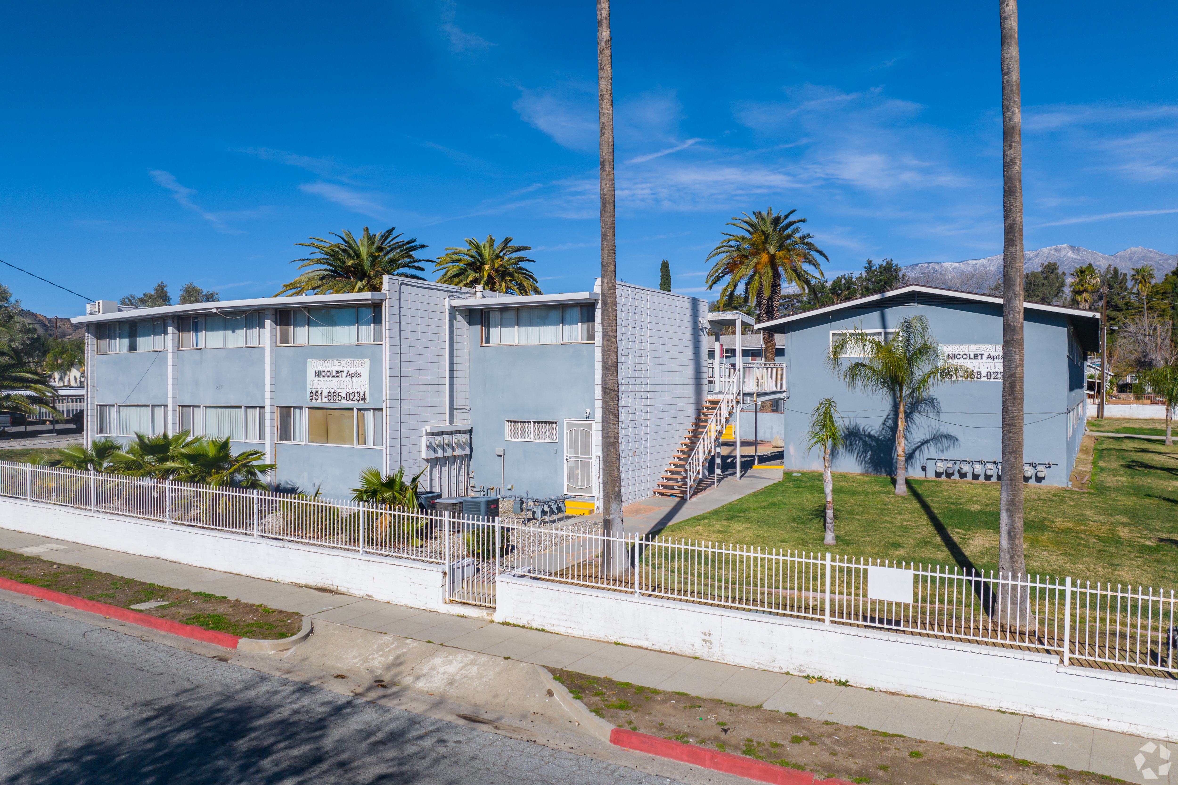 A building with a blue facade and palm trees in front.