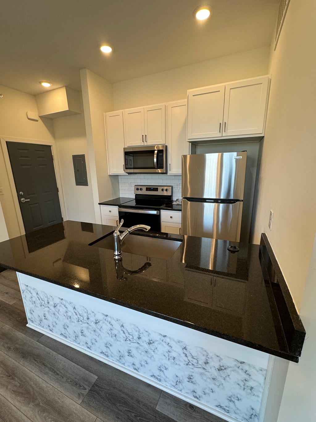 a kitchen with a black counter top and a stainless steel refrigerator