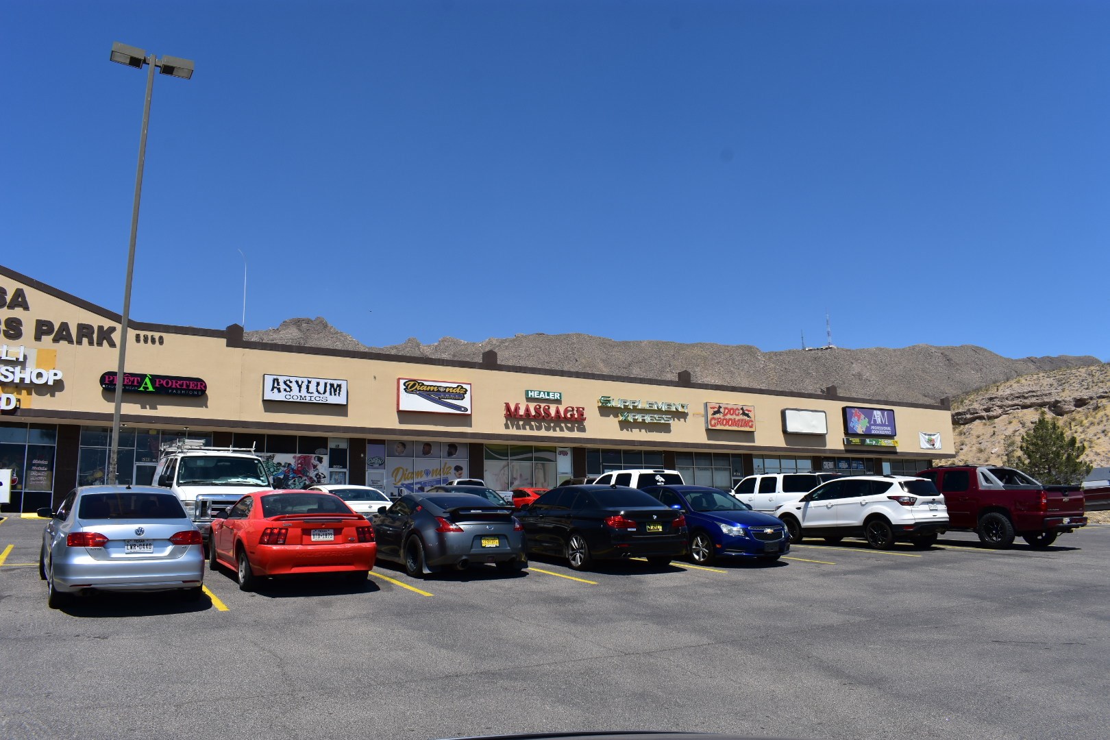 a parking lot full of cars in front of a shopping center