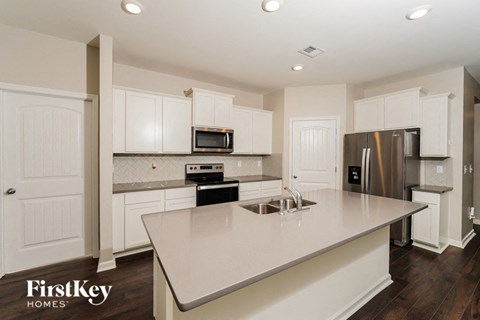 A kitchen with a stainless steel refrigerator and a white island.