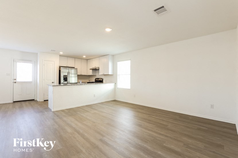 A spacious kitchen with wooden floors and white walls.