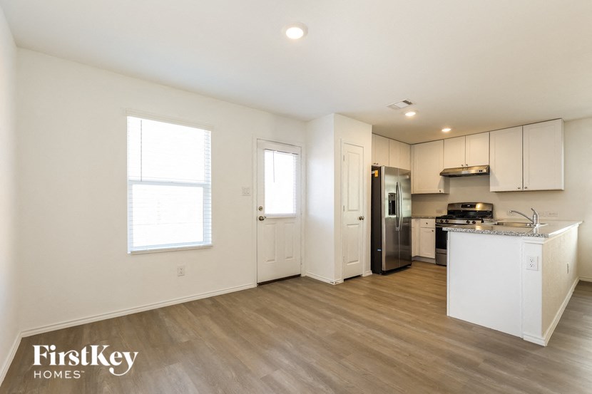 A kitchen area with a refrigerator, sink, and cabinets.
