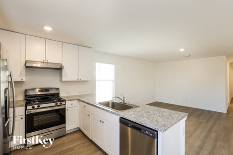 A kitchen with white cabinets and a granite countertop.