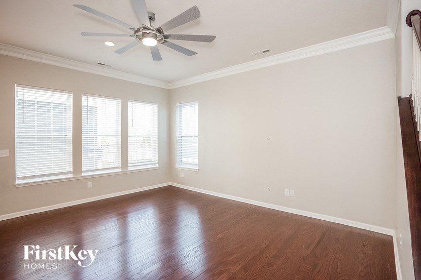 an empty living room with a ceiling fan and wood floors