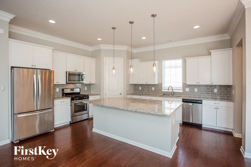 a kitchen with white cabinets and a marble counter top