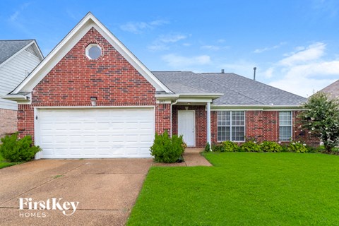 a brick house with a white garage door and a lawn