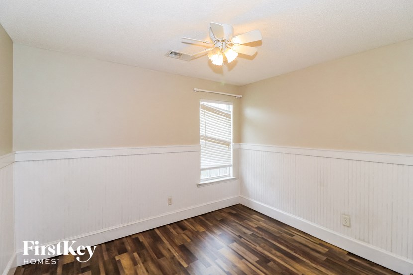 a bedroom with white walls and wood floors and a ceiling fan