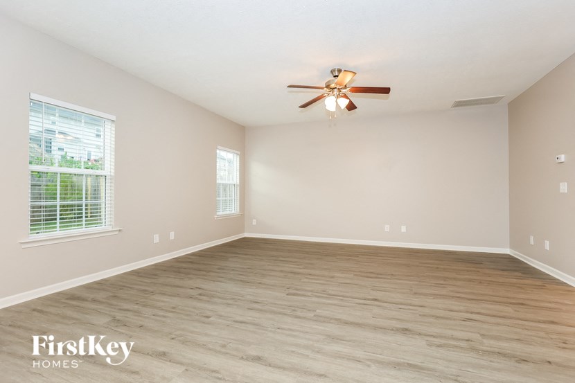 a clean and empty living room with a ceiling fan