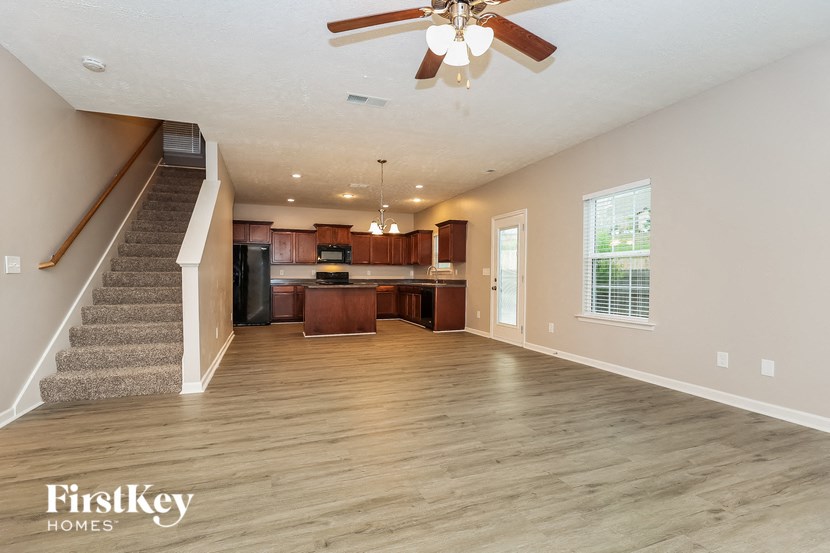 an empty living room and kitchen with a ceiling fan