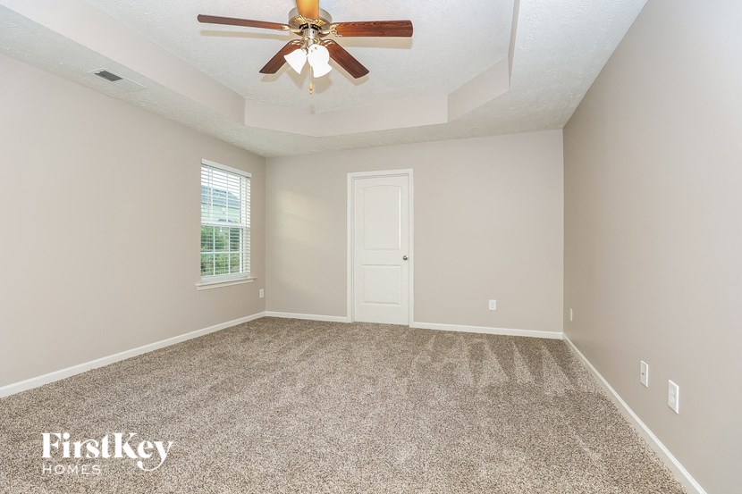 an empty living room with a ceiling fan and a window